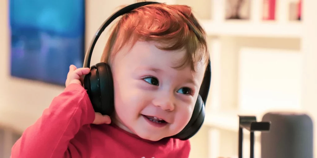 Prática baseada em evidências: bebê está com fones de ouvido e sorrindo