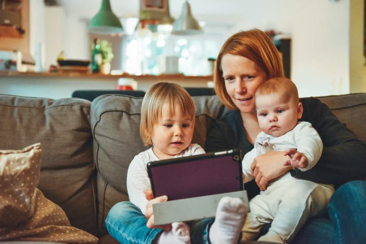 Mãe com duas crianças de colo olhando para um tablet. RUBI: método para crises