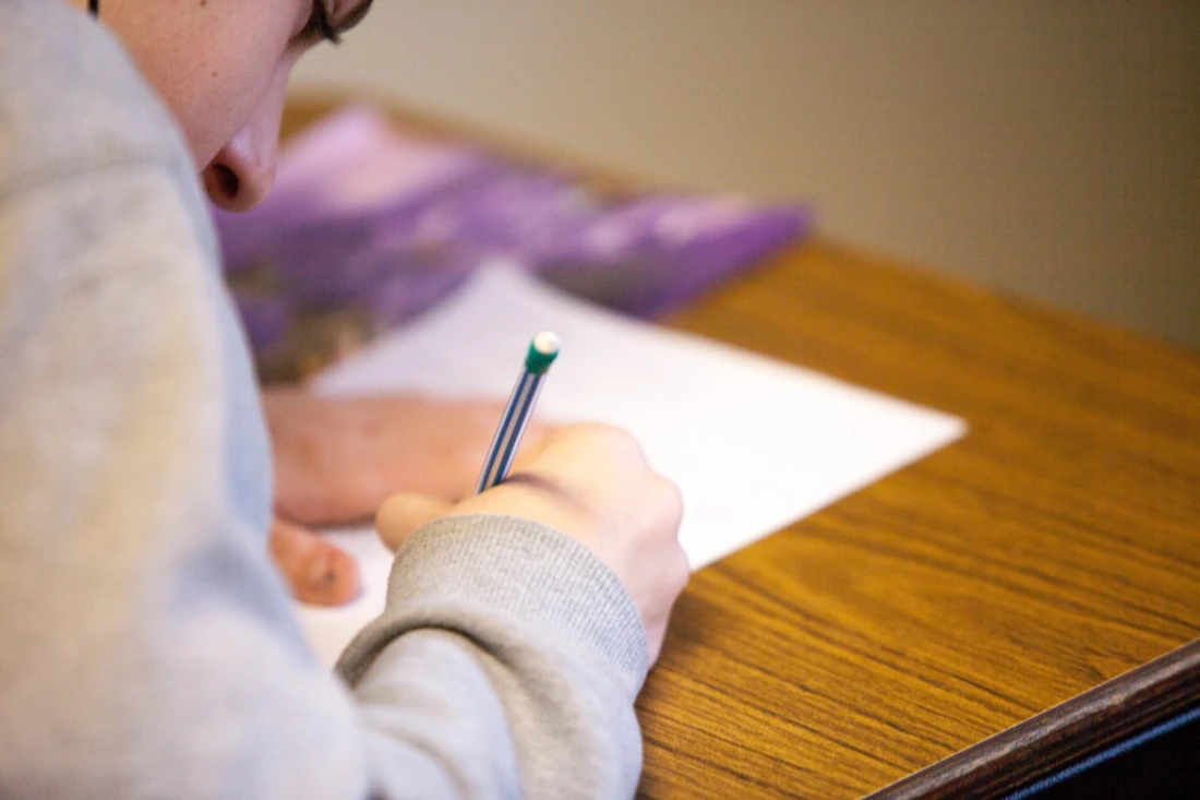 Ursinho Pooh: Pessoa escrevendo com a mão direita em um papel sobre a mesa.