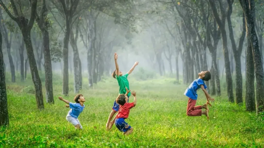 Crianças pulando em um campo aberto em meio a chuva.