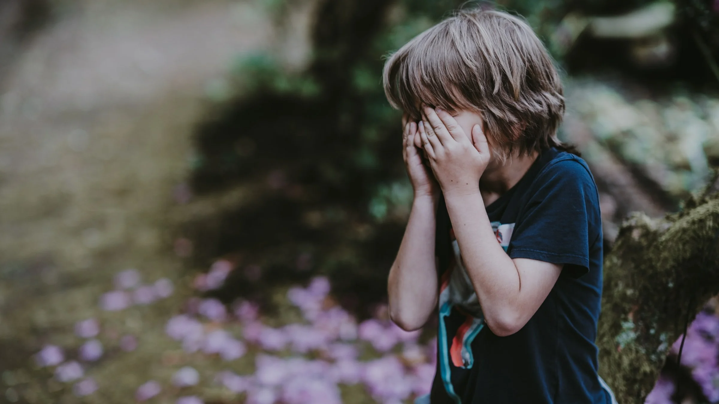crises de agressividade no autismo: criança segura o rosto com as mãos