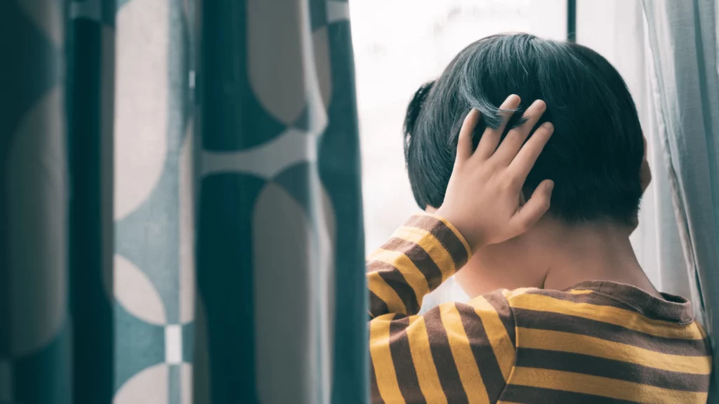 hiperssensibilidade: imagem mostra menino na janela com as mãos sob os ouvidos
