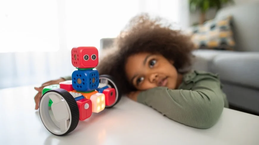 síndrome de asperger: criança segura um brinquedo e está com braços apoiados na mesa