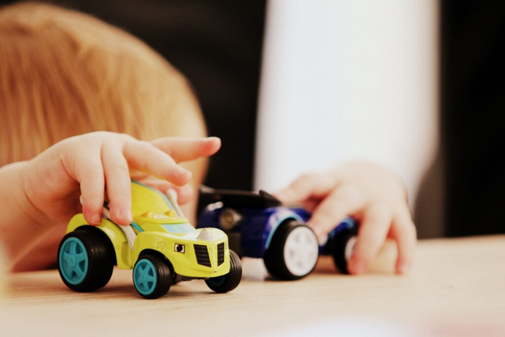 sintomas de autismo: criança brinca com dois carrinhos de brinquedo