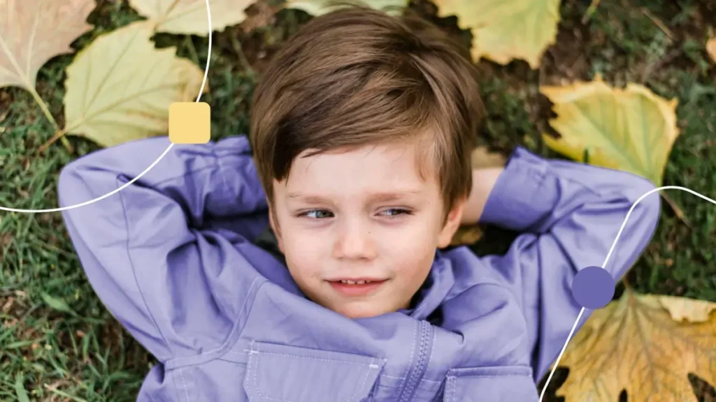 Autismo tem cura: Menino deitado em um parque com diversas folhas.