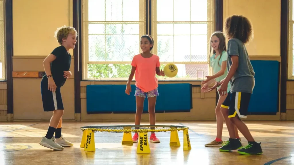 RUBI cooperação e comunicação funcional: Crianças brincam com uma bola em uma quadra