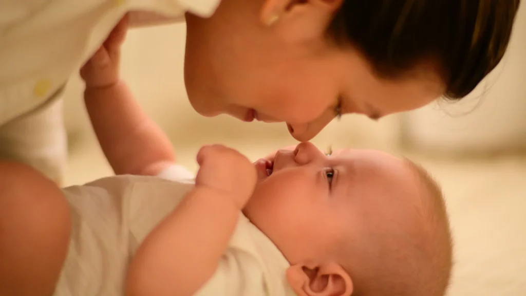 causas do autismo: bebê está deitado e mãe encosta nariz no dele
