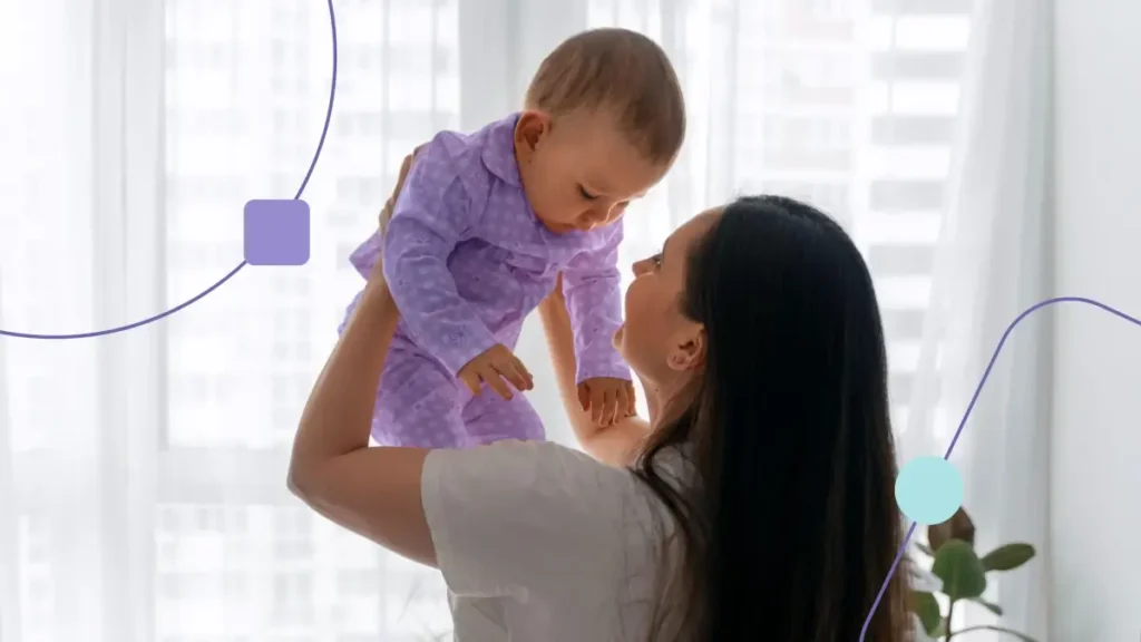 Mãe levantando bebê. Ela tem feição de dúvida sobre quais causas do autismo.