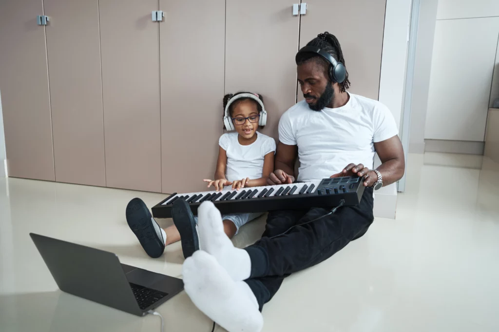 pai e filha de fones de ouvido tocando teclado
