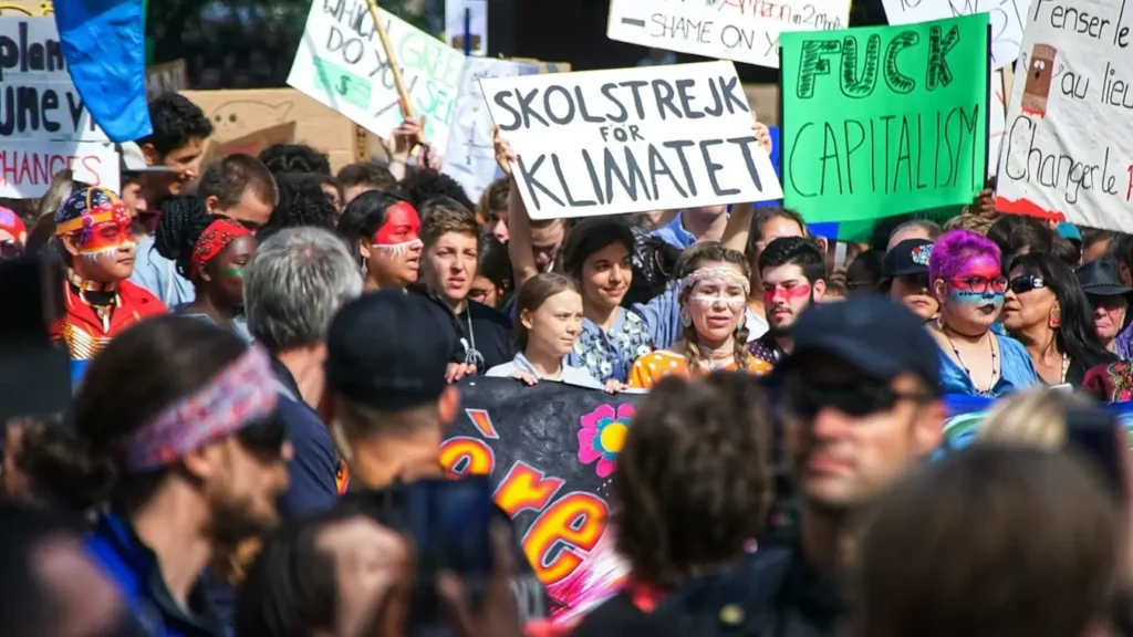 Greta Thunberg e autismo: imagem mostra manifestação e greta ao centro de várias pessoas com cartazes em sueco