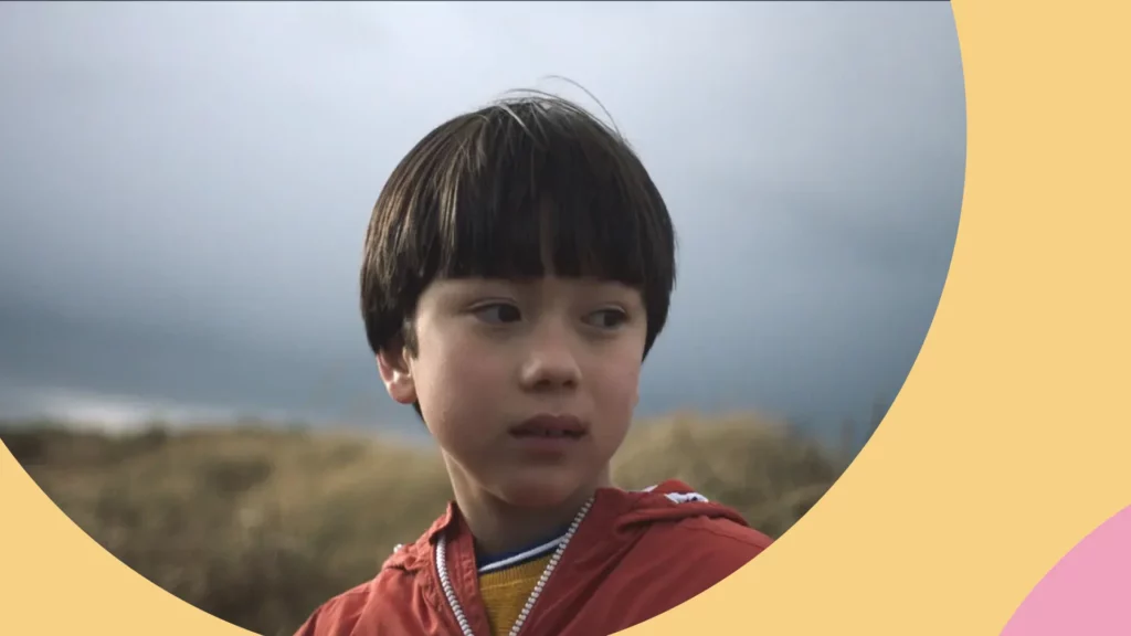 Menino asiático de jaqueta vermelha olhando para o lado. A imagem faz parte do documentário “O que me faz pular”.