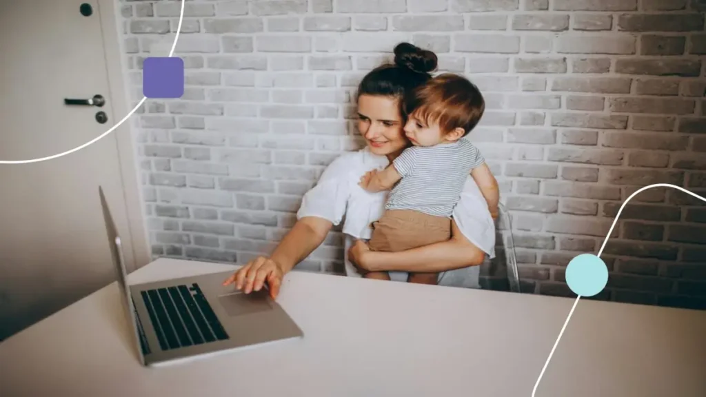 Mãe com filha no colo. Ela busca em seu notebook informações sobre Orientação parental