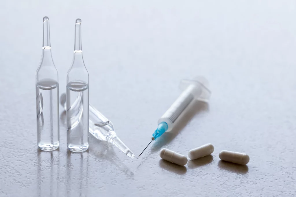 seringas, pílulas e ampolas de remédios em uma mesa