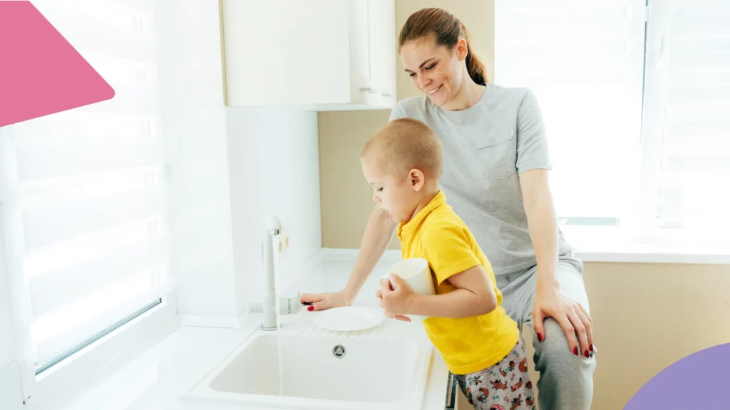Mãe ensina filho a lavar os pratos na pia.