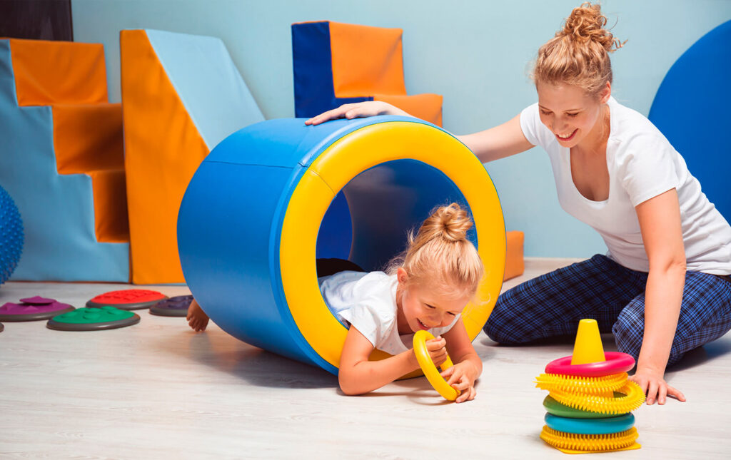 mulher e criança brincando em uma sala de integração sensorial