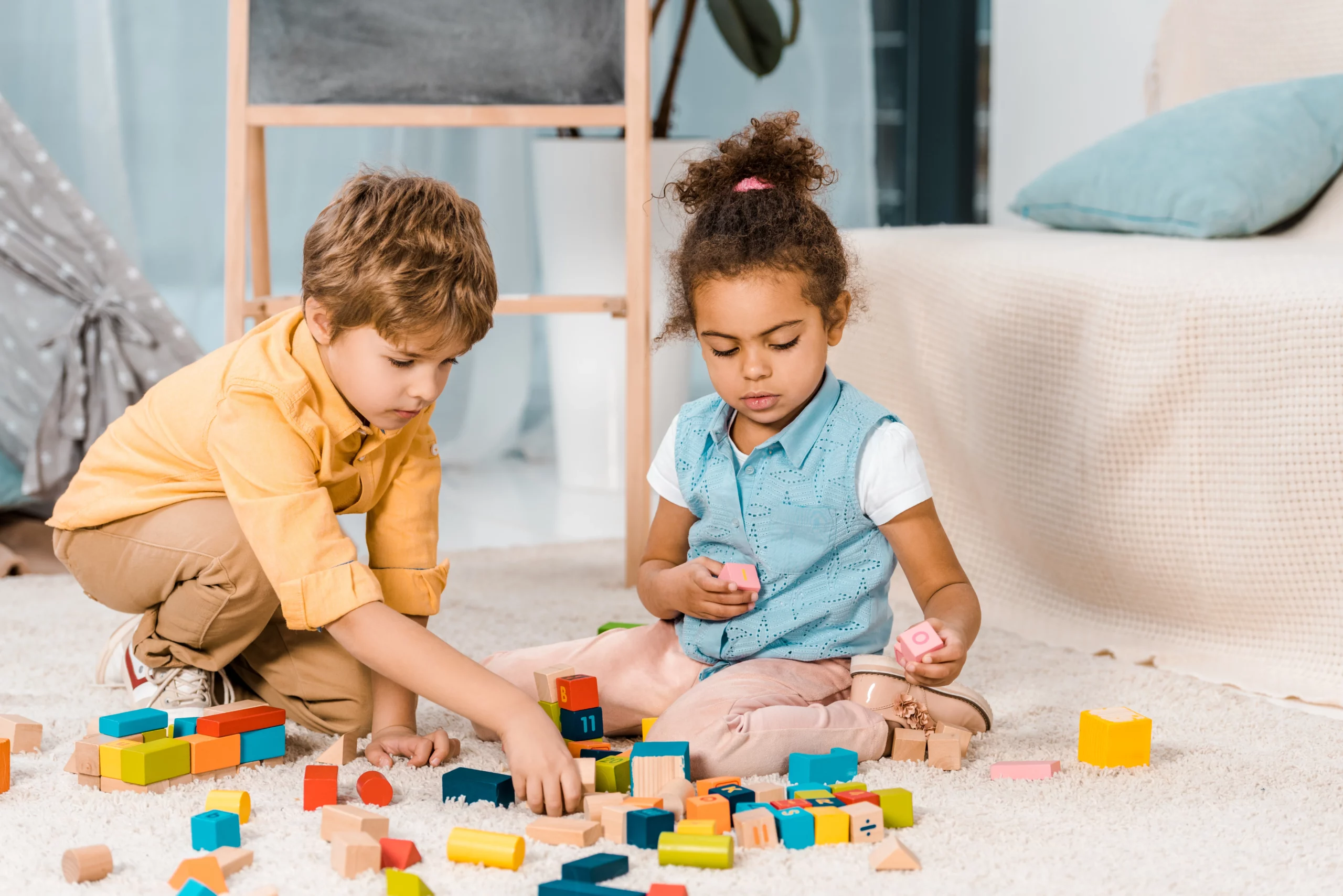 duas crianças brincando com blocos coloridos no chão