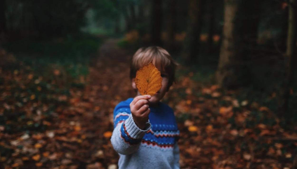 Criança segurando uma folha em frente a seu rosto