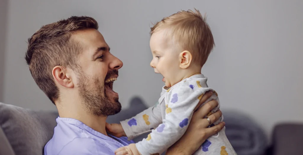 Pai com filho no colo. Ele pratica o desenvolvimento da fala de seu filho.