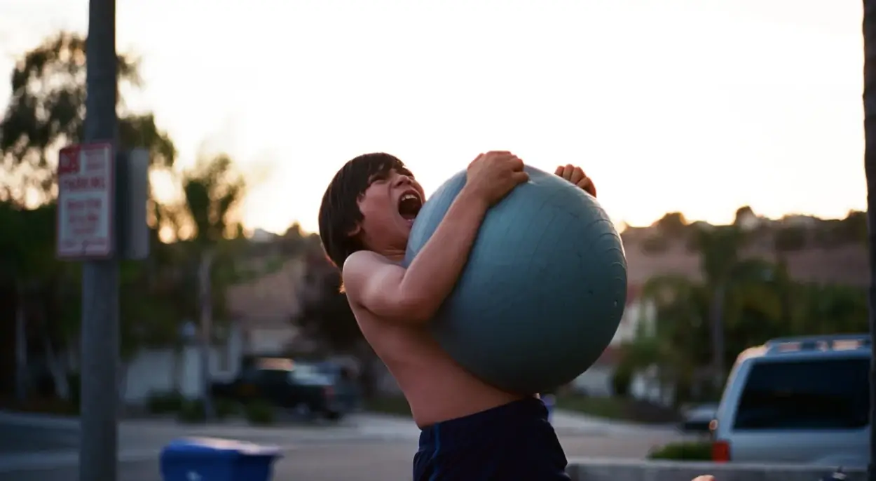 menino gritando abraçado com uma bola