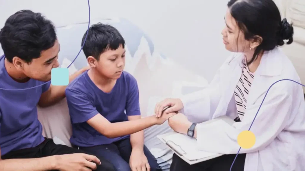 Terapeuta ABA atendendo menino autista com seu pai ao lado.