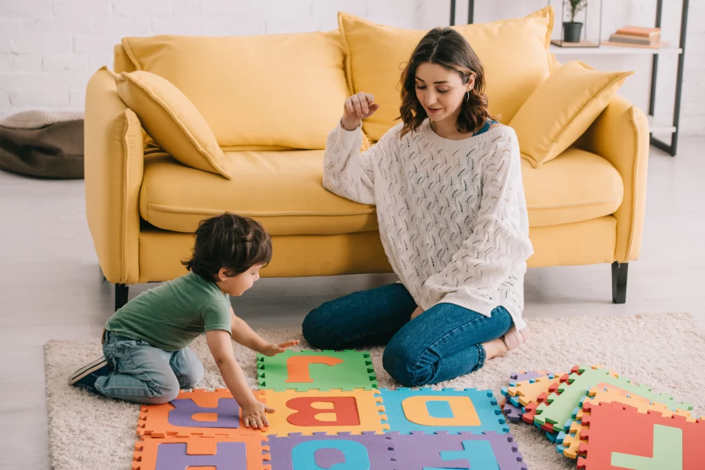 mulher e criança sentados no chão da sala brincando com letras coloridas