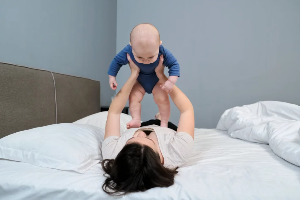 mulher levantando bebê deitada na cama 