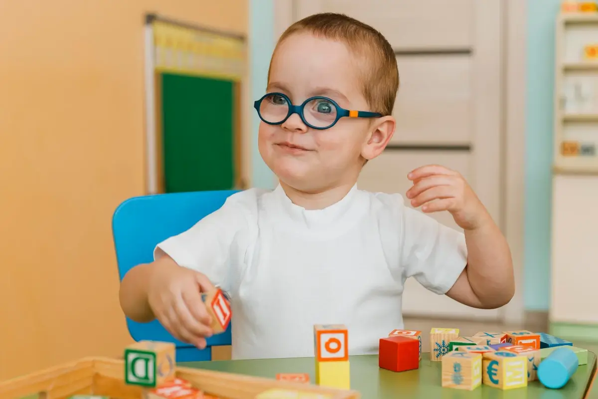 Bebê com autismo infantil sentado e brincando com brinquedos em uma mesa.