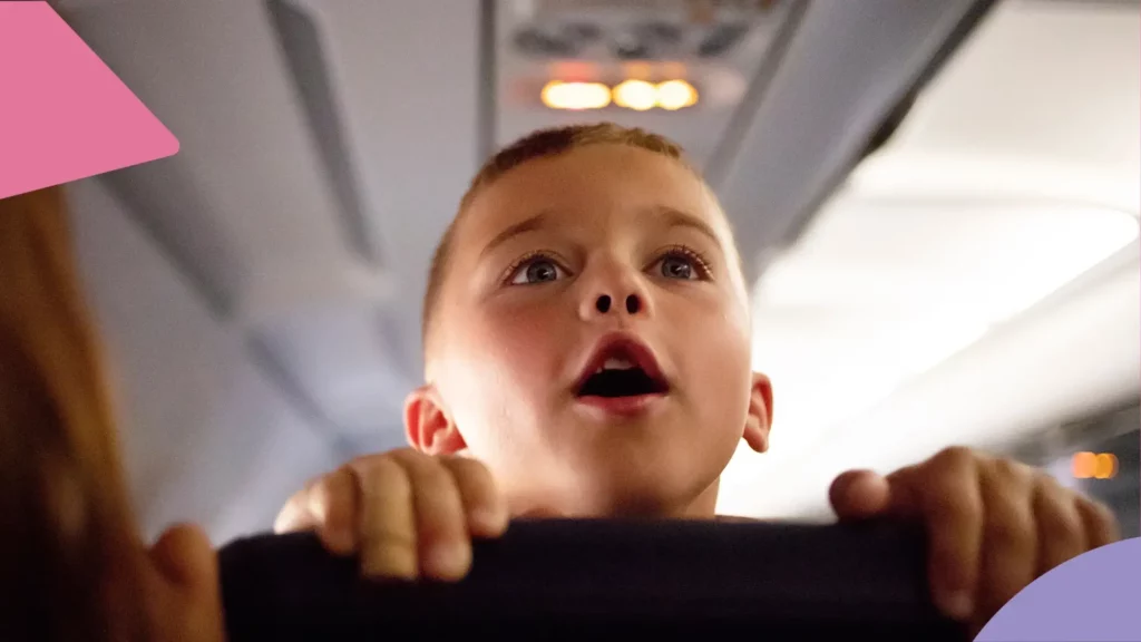 Falta de autonomia: criança apoiada em transporte de avião, olhando para o fundo do transporte, com os lábios entreabertos de surpresa.