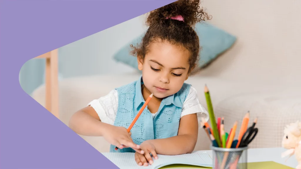 Pequena menina sentada à mesa, junto a seu caderno, enquanto usa a borracha e o lápis no próprio caderno. leitura e escrita no autismo