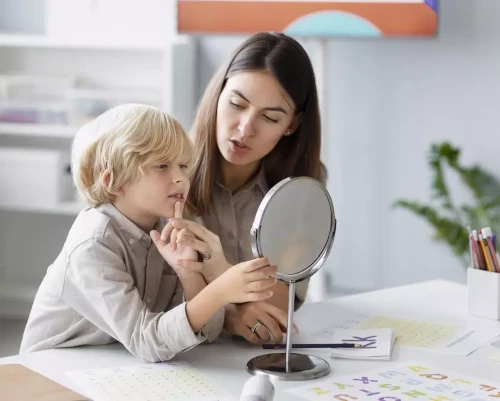 Mãe ajudando seu filho a praticar exercícios de fonoaudiologia para auxiliam em sua apraxia da fala.
