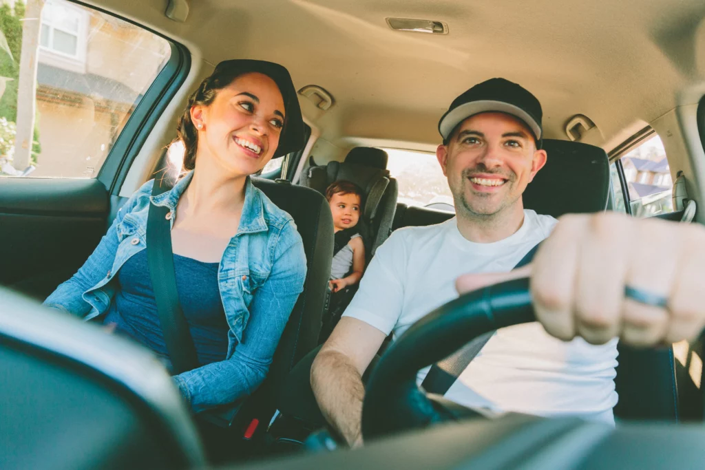 uma família branca com uma mulher, um homem e uma criança estão dentro de um carro