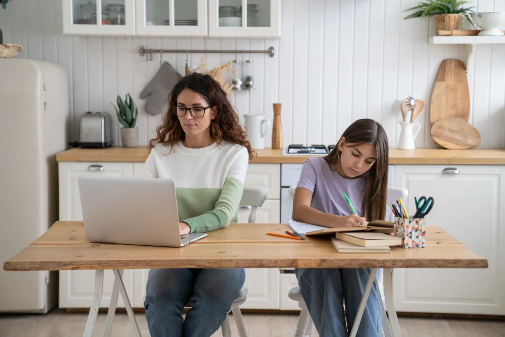 mãe e filha sentadas lado a lado em uma mesa de madeira
