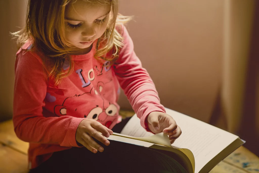 menina folheando um livro sozinha