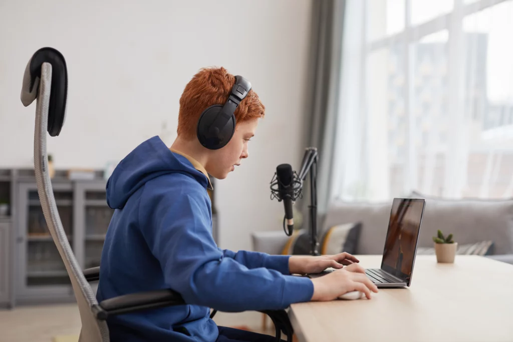 menino ruivo sentado na frente do computador com fone de ouvido