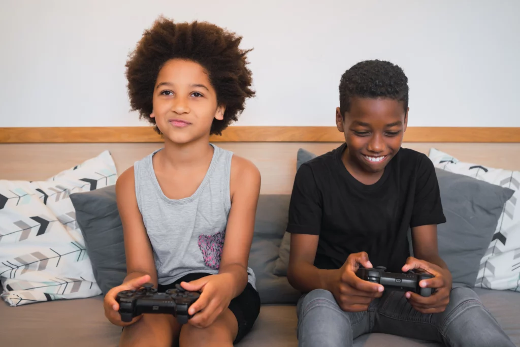dois meninos jogando videogame no sofá 