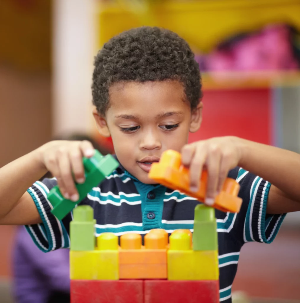 menino usando blocos coloridos na escola