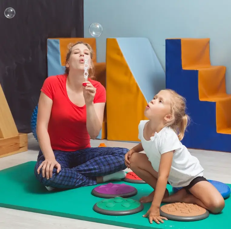 Terapia ABA: terapeuta Genial brincando com criança de fazer bolhas de sabão