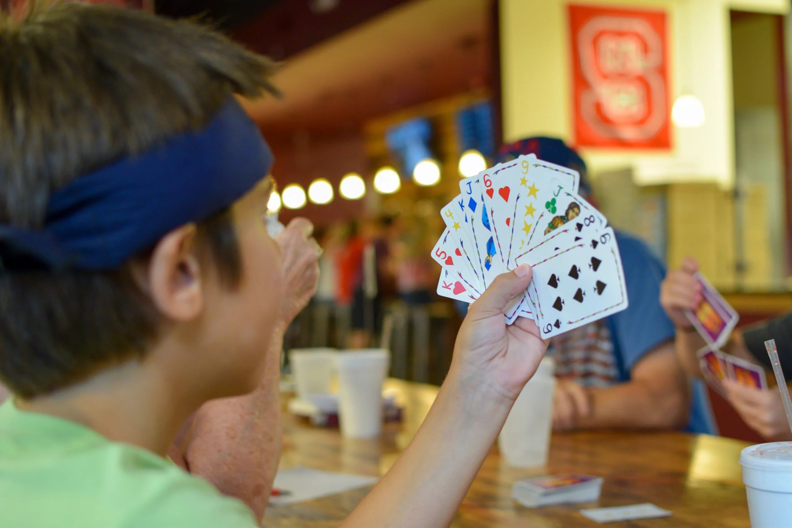 menino de costa segurando cartas coloridas de baralho 