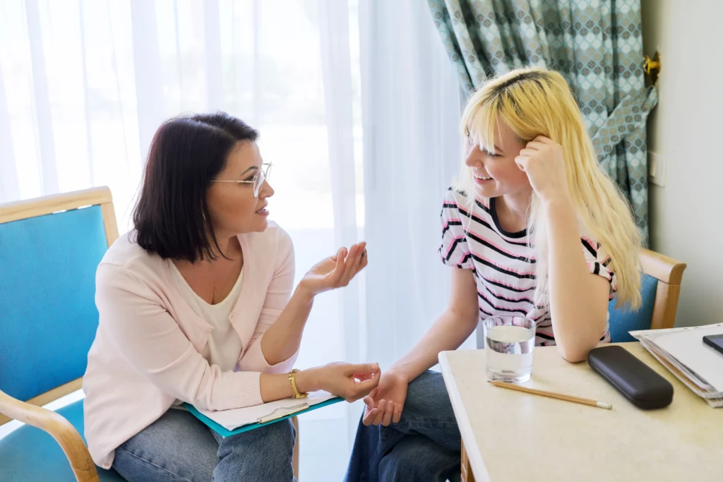 mulher conversando com adolescente sentadas em uma mesa