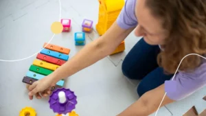 Terapeuta arrumando brincando em chão de clínica de autismo.