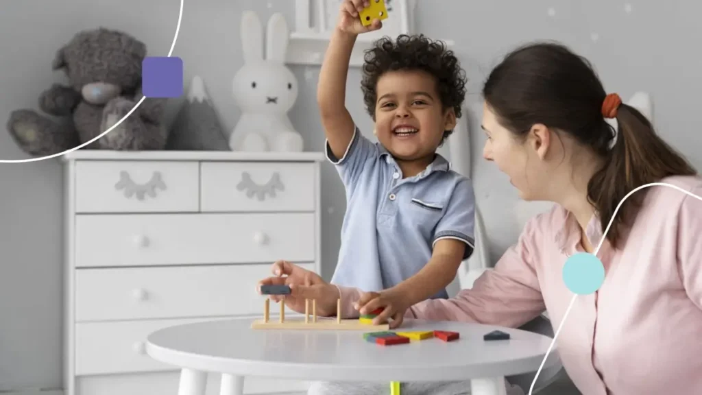 Autismo na Amil: criança levantando um cubo com a mão direita. Ela sorri por estar se divertindo com terapeuta.