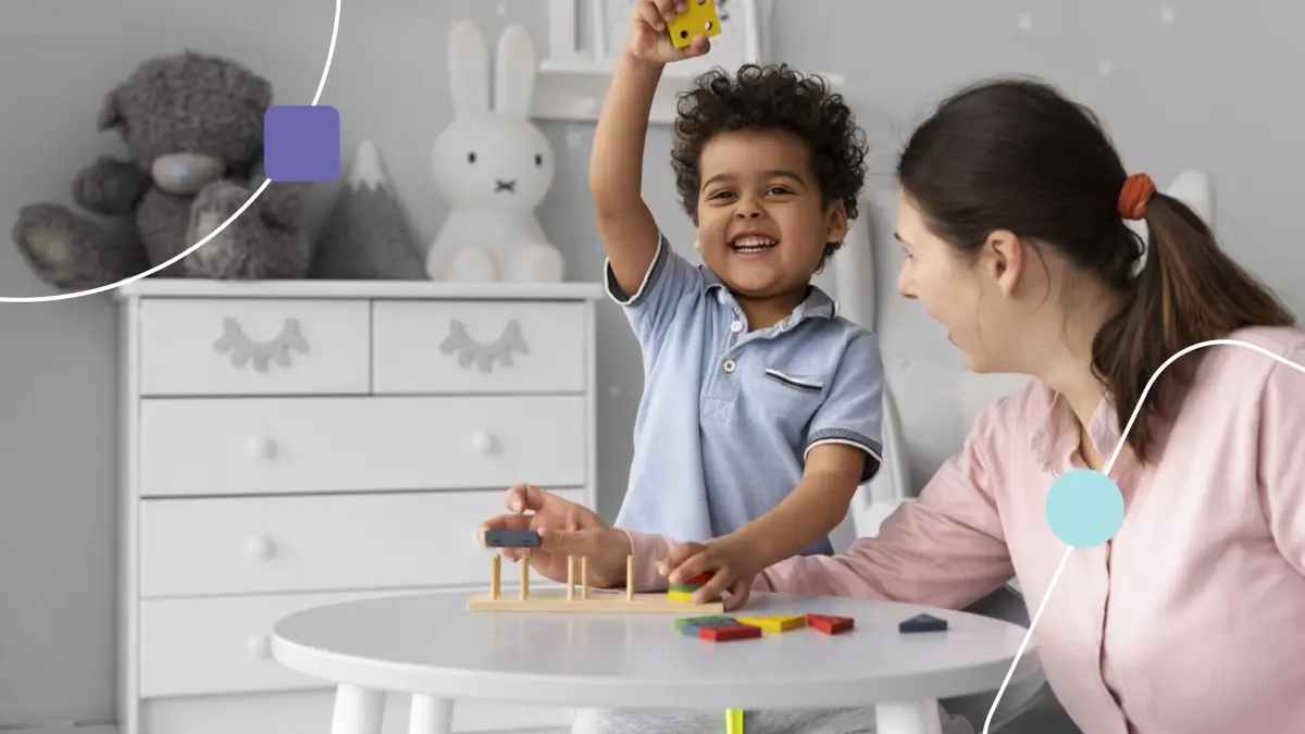 Autismo na Amil: criança levantando um cubo com a mão direita. Ela sorri por estar se divertindo com terapeuta.