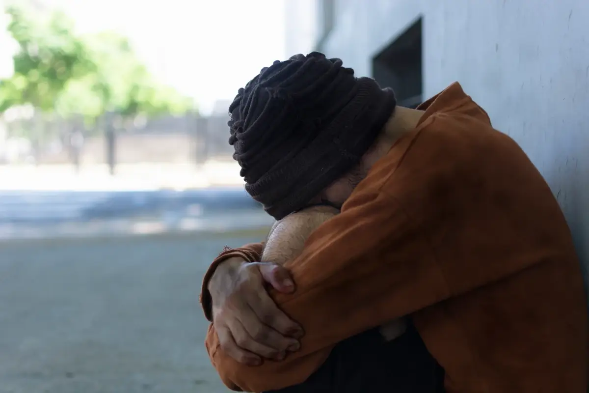 Homem com o rosto sobre os ombros em sinal de tristeza. Ele representa como Pessoa autista lida com o luto.