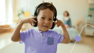 Criança com Hipersensibilidade usando fones de ouvido e com as mãos nos ouvidos.