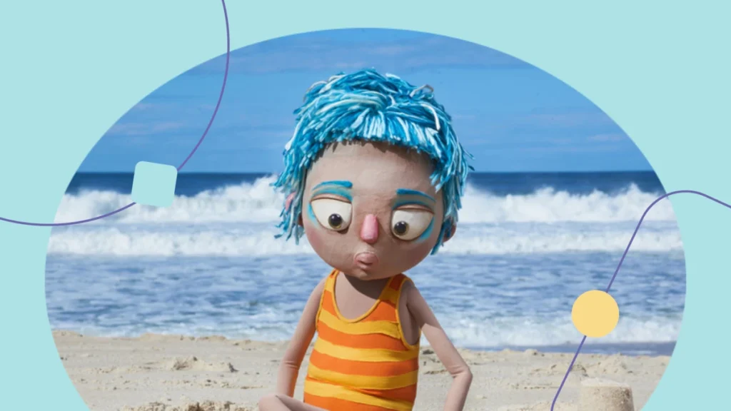 Personagem da peça de teatro infantil Azul sentado na praia. Ele constrói um castelo de areia com as mãos.