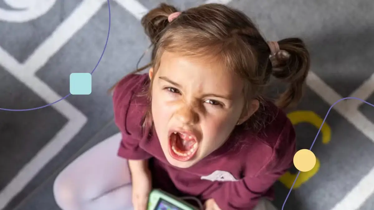 Menina jogando video game e gritando. Ela mostra um comportamento desafiador para sua família.