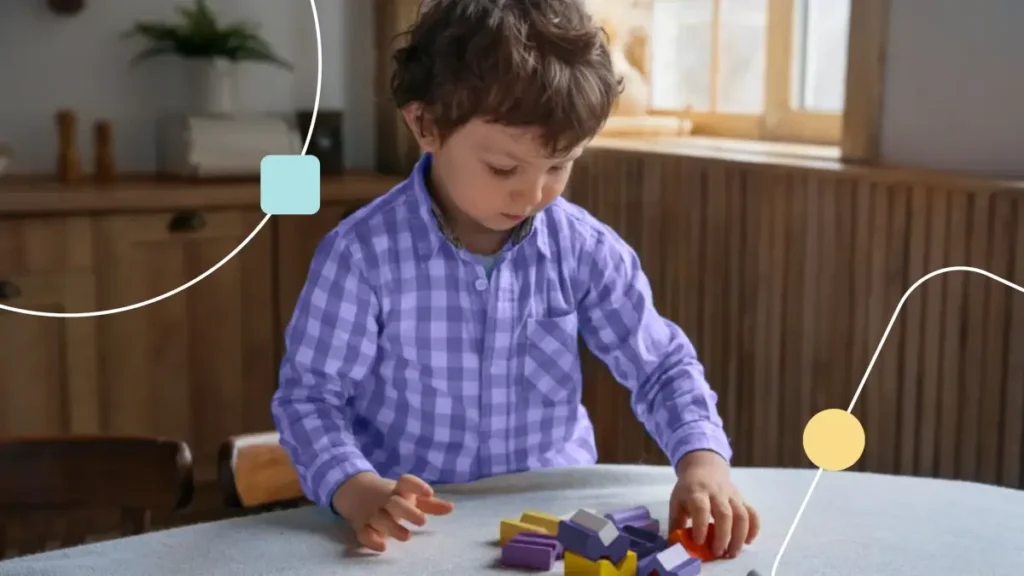 Menino com transtornos neurodivergentes. Ele está brincando com blocos coloridos.