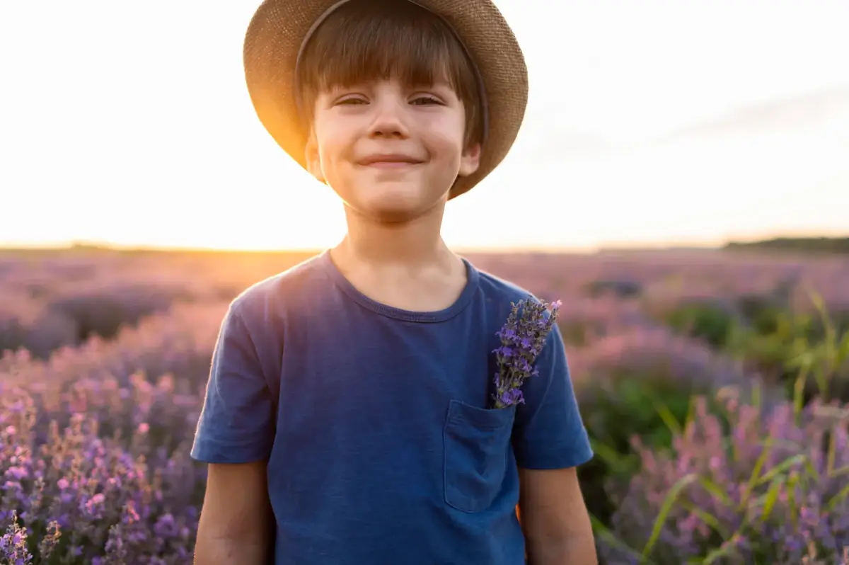 Menino com autoconfiança em um jardim com flores roxas.