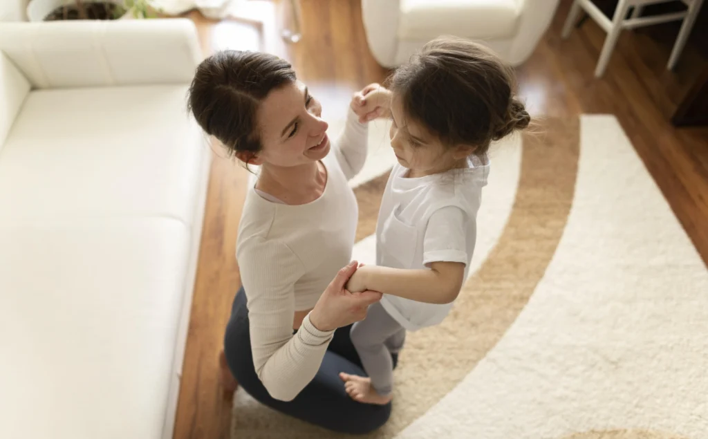 mãe segurando filha sobre os joelhos no chão da sala 