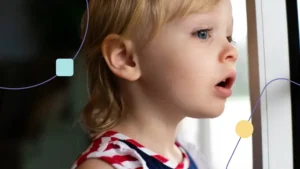 Menina com autismo moderado olhando para fora de sua casa por uma janela.